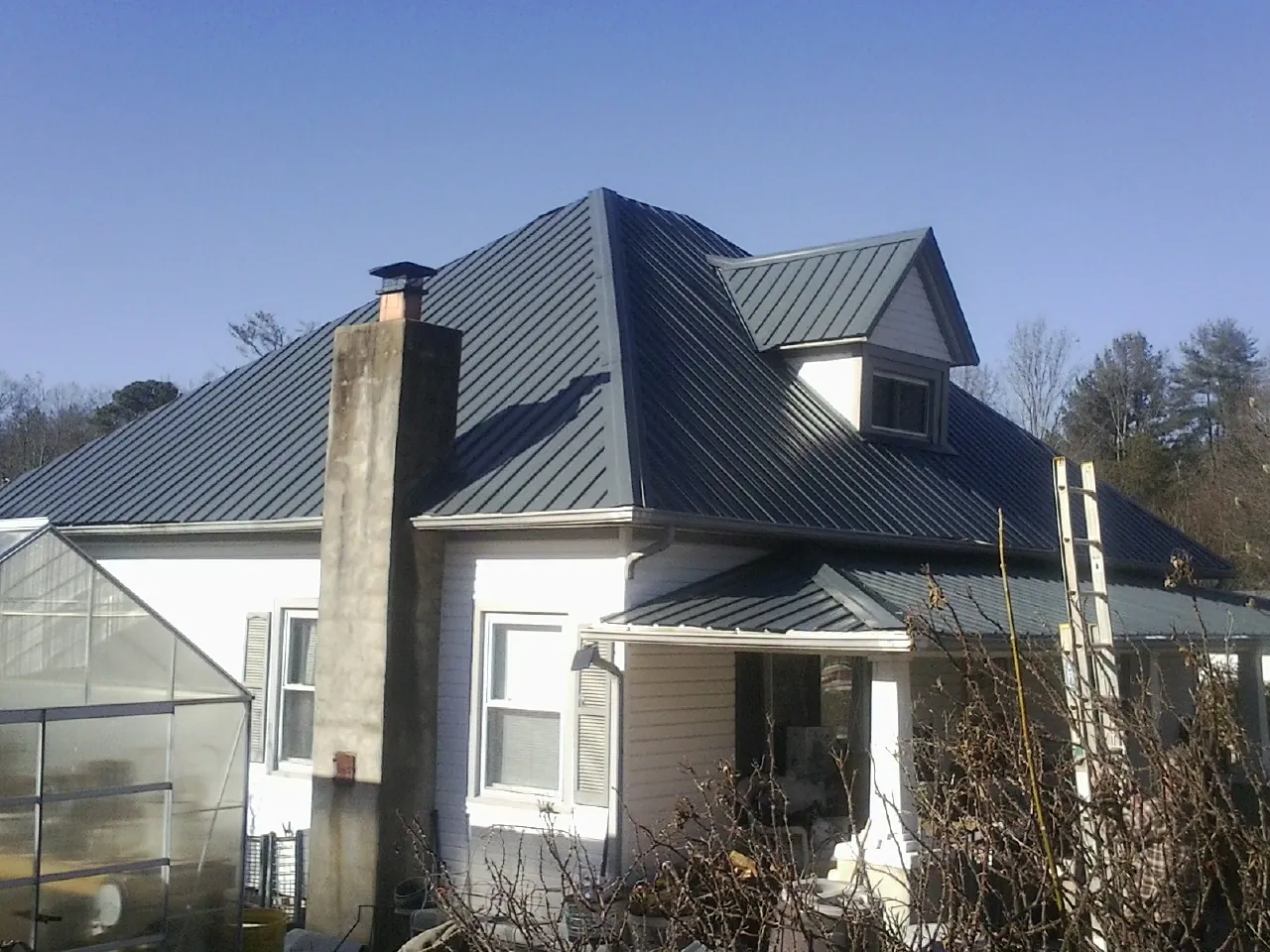 Dark blue standing seam metal roof on a white farmhouse with dormer — Slate & Tile Roof Repair by Roofing Brothers in Latrobe