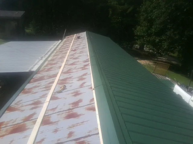 Old rusted panels beside newly installed green metal roofing — Wind Damage Roof Repair by Roofing Brothers in Latrobe