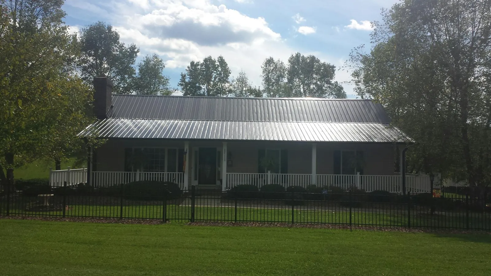 Gray metal roof on a brick ranch with a full width front porch — Gutter Guard Installation work by our crew in Latrobe