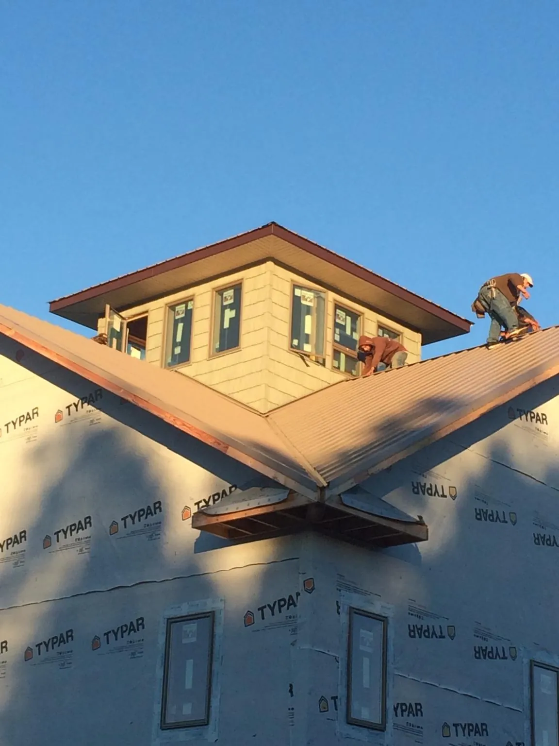 Roofers working around a rooftop cupola on a new metal roof at sunset — Roof Waterproofing in Latrobe by Roofing Brothers